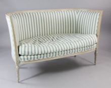 A Louis XVI style carved beech settee, upholstered in blue striped fabric, carved with bell husk