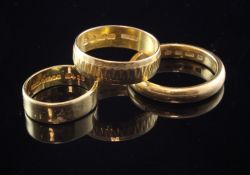 Three 22ct gold wedding bands, one with engraved decoration, 21 grams, various sizes.