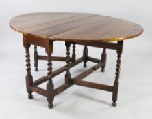 An 18th century walnut oval gateleg dining table, with barley twist supports united by stretchers,