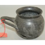 An Etruscan Bucchero ware single handled cup, c. 6th century BC, of globular form with a flat looped