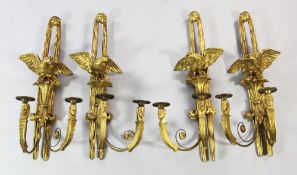 A set of four French Empire style carved giltwood wall lights, each with eagle and fleur de lys