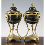 A pair of French Empire style marble and ormolu lidded urns, each with pineapple finials, satyr