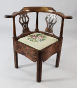 An 18th century yew wood corner chair, with pierced splat back and floral tapestry drop in seat