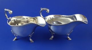 A pair of 1930's silver sauceboats, with gadrooned borders and flying scroll handles, on hoof