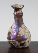 A Roman amber glass flask, c.2nd century AD, with flared neck and aubergine mineral iridescence,