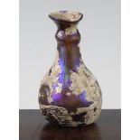 A Roman amber glass flask, c.2nd century AD, with flared neck and aubergine mineral iridescence,