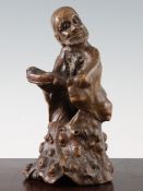 A Chinese rootwood carving of a luohan, 18th century, the figure holding a bowl, carved from the