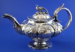 A William IV silver melon shaped teapot, embossed with flowers and scroll, on pedestal foot with