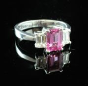 A platinum, pink sapphire and diamond three stone ring, the emerald cut pink sapphire weighing