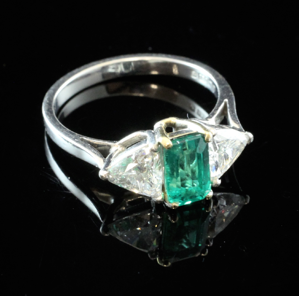 An 18ct white gold, emerald and diamond three stone ring, the central emerald weighing 1.05ct and