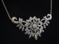 A white gold and diamond cluster pendant necklace, of pierced scroll design, set with round cut