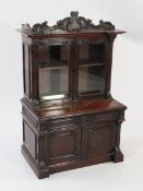 A Victorian mahogany miniature bookcase, with scrolling acanthus pediment above two glazed doors,