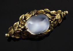 A 14ct gold and cabochon moonstone set brooch, the setting decorated with flowers and leaves,