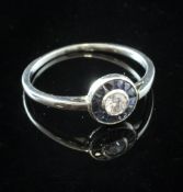 A white gold, sapphire and diamond target ring, set with central round cut diamond bordered with