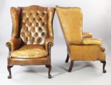 A pair of brown leather wingback armchairs, with buttoned backs and brass studded decoration, on