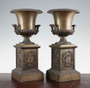 A pair of late 19th / early 20th century French campana shaped bronze urns, each on a square