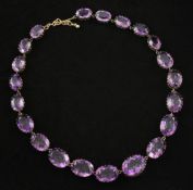 A gold and amethyst fringe necklace, set with twenty one graduated oval cut, claw set amethysts,