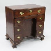 A George III mahogany kneehole desk, with central recessed cupboard door and an arrangement of seven