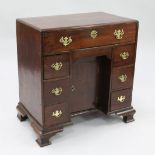 A George III mahogany kneehole desk, with central recessed cupboard door and an arrangement of seven