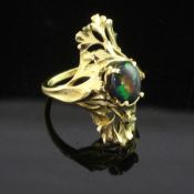 A French 18ct gold and black opal up-finger ring, with oval cut stone and pierced foliate setting,