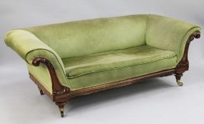 A Victorian mahogany settee, upholstered in a pale green fabric, with leaf carved scrolling arms, on