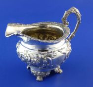 A Victorian silver circular cream jug, with engraved monograms and embossed with scrolling