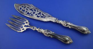 A pair of Victorian silver fish servers, with pierced blade and tines, ornate scroll handles and