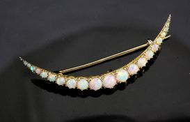 An early 20th century gold and silver, graduated white opal crescent brooch, in gilt tooled
