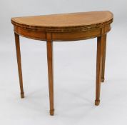 An Edwardian satinwood and rosewood crossbanded demi-lune folding card table, with green baize