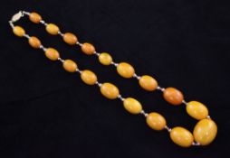 A single strand graduated amber oval bead necklace, with silver gilt clasp and white metal