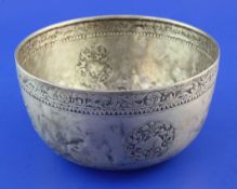 An early 20th century Burmese? silver circular bowl, with embossed foliate border and decorated with