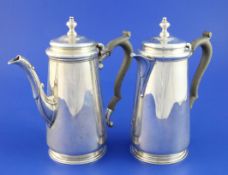A George V silver cafe au lait pair, of tapering cylindrical form, with acanthus leaf capped spouts,