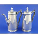 A George V silver cafe au lait pair, of tapering cylindrical form, with acanthus leaf capped spouts,