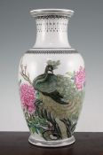 A Chinese famille rose ovoid vase, Republic period, finely painted with a peacock perched amid