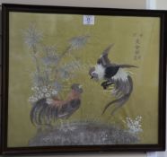 A Japanese embroidered silk panel of two fighting cockerels, the cockerels beside bamboo and flowers