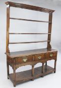 An 18th century oak dresser, the open plate rack with three shelves above three frieze drawers and