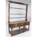 An 18th century oak dresser, the open plate rack with three shelves above three frieze drawers and