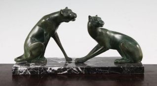 A French Art Deco green patinated metal model of two panthers, on a rectangular marble base,