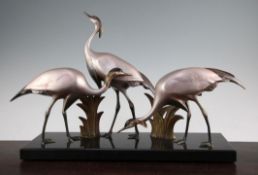 Armand Sinko. A French Art Deco patinated and cold painted bronze figure group of three cranes, on a