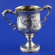 A George III Irish silver two handled pedestal cup, with leaf capped scroll handles and later?