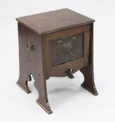 An Arts & Crafts Liberty style oak purdonium, the front with embossed metal panel and unusual