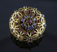 A French 18ct gold, ruby and sapphire set clip brooch by Mellerio, Paris, of raised, pierced