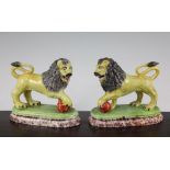 A pair of British pottery figures of lions, c.1820, the yellow glazed lions modelled on oblong