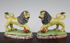 A pair of British pottery figures of lions, c.1820, the yellow glazed lions modelled on oblong
