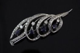 An 18ct white gold, sapphire and diamond brooch, of openwork scrolling design, set with pear