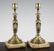 A pair of French Empire style figural bronze candlesticks, each column modelled as a standing