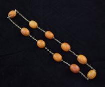 A single strand amber bead necklace, strung with ten oval butterscotch coloured beads, gross