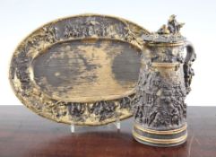 A late 19th century Dutch mixed metal tankard and oval tray, relief decorated with figural village