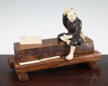 A Japanese ivory, bronze and wood okimono of a carpenter, early 20th century, the carpenter seated