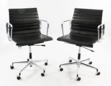 A pair of Vitra Charles Eames EA117 aluminium desk chairs, with black leather back and seat, factory